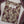 A folded beige kurta with a purple and brown floral print, featuring a silver-toned decorative collar and a white brand label reading 'sajh dach'. The kurta is styled with a matching purple and beige embroidered dupatta on a white background.
