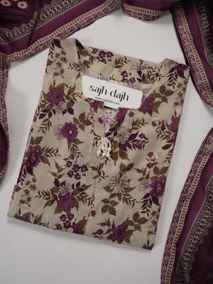 A folded beige kurta with a purple and brown floral print, featuring a silver-toned decorative collar and a white brand label reading 'sajh dach'. The kurta is styled with a matching purple and beige embroidered dupatta on a white background.