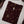 A folded dark maroon fabric piece with small gold floral and dot patterns, shown on a white surface with matching draped fabric partially visible at the edges.