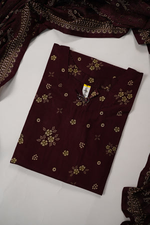 A folded dark maroon fabric piece with small gold floral and dot patterns, shown on a white surface with matching draped fabric partially visible at the edges.